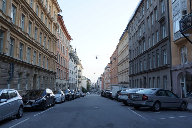 Gata i centrala Stockholm med lägenhetshus på vardera sida och bilar som står parkerade längs gatan.