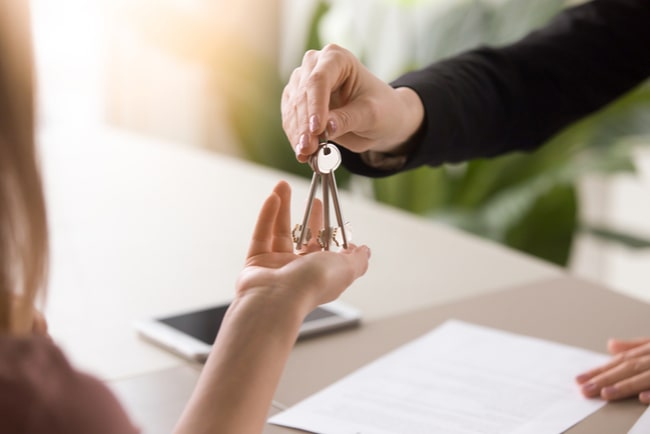 kvinna tar emot nycklar av en fastighetsförmedlare